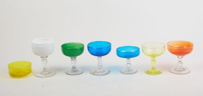 several different colored wine glasses are lined up on a white surface