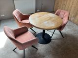 pink chairs and a round table in a room with a radiator