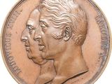 an image of a bronze medal with two heads of a man and a woman