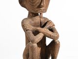 an old wooden statue of a monkey sitting on a white surface
