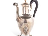 an antique silver tea pot with a black handle sitting on a stand
