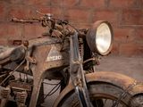 an old motorcycle parked in front of a brick wall