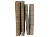 several old books are stacked on top of each other on a white surface