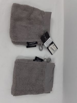 Deux serviettes grises sont posées sur une surface blanche, à côté d'une paire de ciseaux