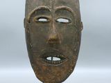 image d'un masque en bois sur un support sur fond blanc