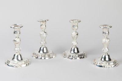 trois bougeoirs en argent sont posés les uns à côté des autres sur une table
