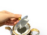 a hand that is holding a tea pot with a lid