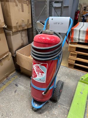 un extincteur rouge posé sur un chariot dans un entrepôt