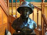 une statue représentant une femme coiffée d'un chapeau, sur les marches