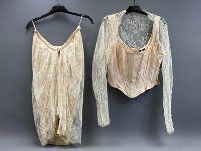 two women ' s lingersuits hanging on a hanger in front of a gray wall