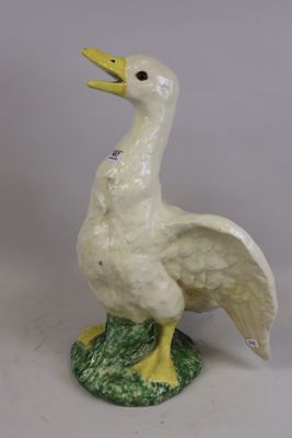 une image représentant une statue de canard blanche et jaune posée sur un socle vert