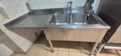 a stainless steel sink in the corner of a public restroom