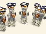 four glass vases with scissors in them on a white surface