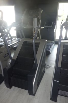deux tapis de course dans une salle de sport, avec un homme debout sur l'un d'eux