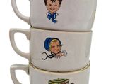 three white cups with cartoon characters on them stacked on top of each other