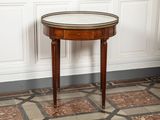 une petite table ronde avec un plateau en marbre, posée sur un sol carrelé
