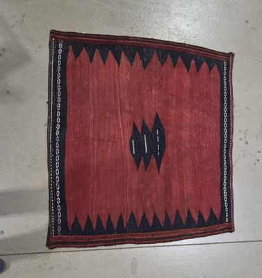 un vieux tapis rouge et noir posé sur un sol blanc
