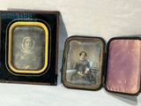 Trois photographies anciennes représentant un homme et une femme sont exposées dans une vitrine