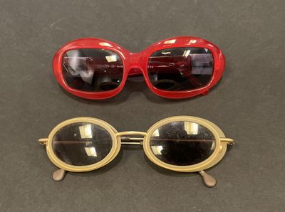 two pairs of red and gold sunglasses sitting on top of a table