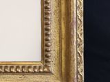 an antique gold frame with a black background and a white wall