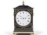 une horloge noire et dorée avec des chiffres romains