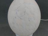 une boule de marbre blanc posée sur une table, avec un socle blanc