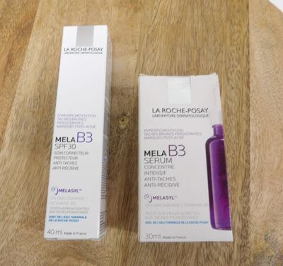 two bottles of melab 3 serum sitting on top of a wooden table