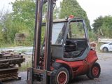 un chariot élévateur garé à côté d'un tas de bois