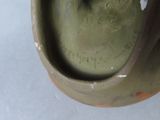 a green vase with writing on it sitting on a table