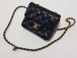 a black purse with a chain around it sitting on a white surface