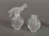 two small glass bottles with a bird on top of them