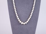 a white pearl necklace on a mannequin display