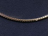 a close up of a gold chain on a black leather surface