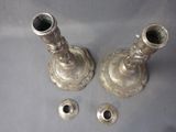 two silver candlesticks sitting on a table next to each other