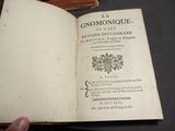 quelqu'un tient un livre ouvert sur une table devant laquelle se trouve une pile de livres