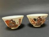 pair of chinese porcelain bowls with figures on them on a table