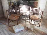 three wooden chairs sitting in front of a fire place