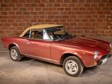a red car with a tan top parked in front of a brick wall