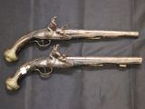 pair of antique silver plated pistols on a black cloth