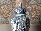 un vase bleu et blanc posé sur une étagère devant un tableau