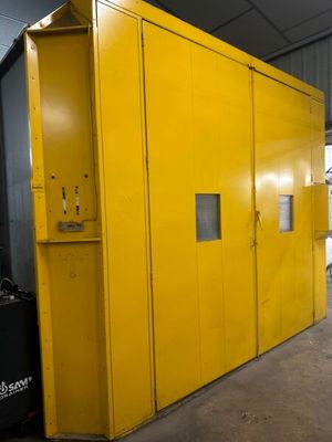 une grande armoire jaune dans un entrepôt, à côté d'une poubelle noire