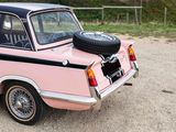 a pink car with a tire on the back of it