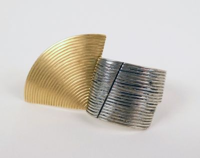 un gros plan d'une bague en argent et en or posée sur une surface blanche