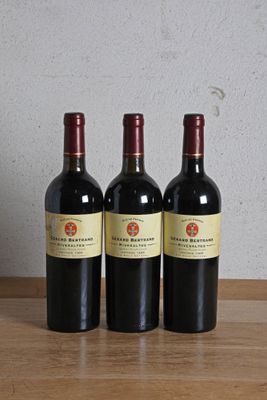 trois bouteilles de vin posées sur une table en bois, à côté d'une bouteille de vin