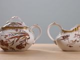 two white and gold teapots sitting on a wooden table