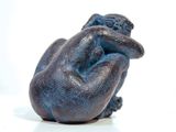 a small statue of a person sitting on a white surface