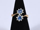 a close up of a gold ring with a blue sapphire and white diamonds