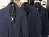 three jackets hanging on a rack in a clothing store