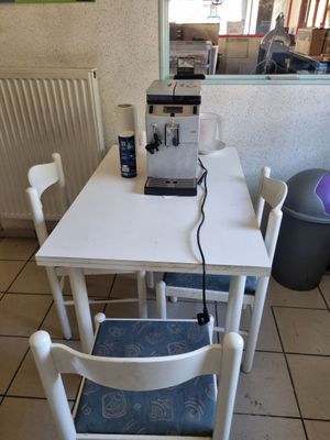 une petite table sur laquelle se trouvent deux chaises et une cafetière