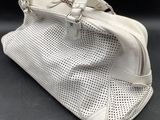 the white purse is on a black surface with a black background